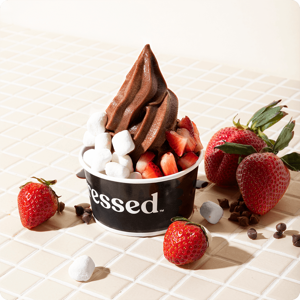 A cup of Chocolate Freeze topped with straberries and marshmallows.